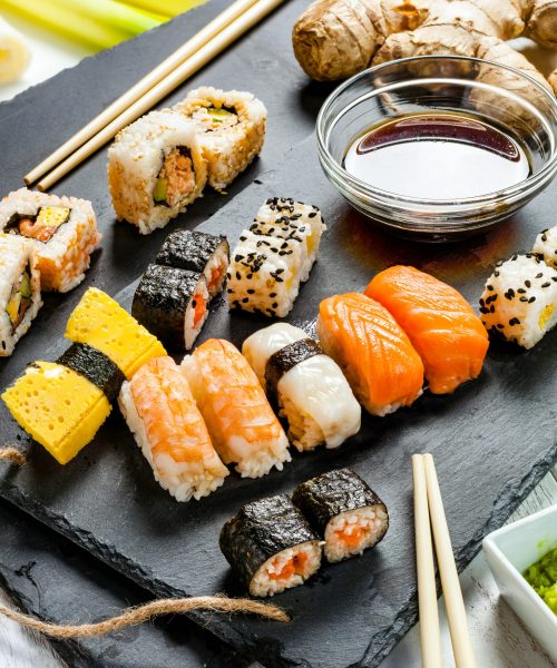 Black slate tray of assorted sushi and rolls.